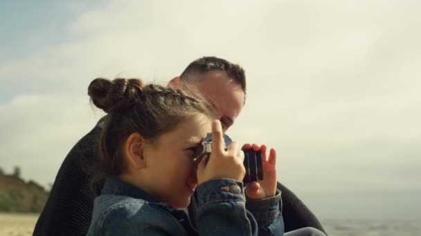 Süßes Kind beim Fotografieren am Strand. Kleines Mädchen hält Fotokamera bei Familienausflug in der Hand — Stockvideo