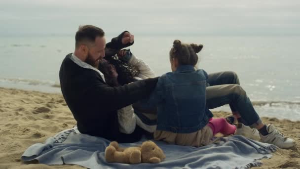 ビーチの砂に抱かれた楽しい家族グループ。海のほとりで抱きしめる幸せな人々. — ストック動画