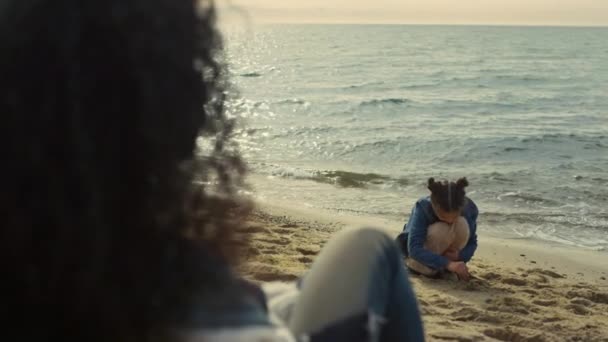 Família sentados juntos praia. Criança brincalhão construindo castelo de areia na costa do mar. — Vídeo de Stock
