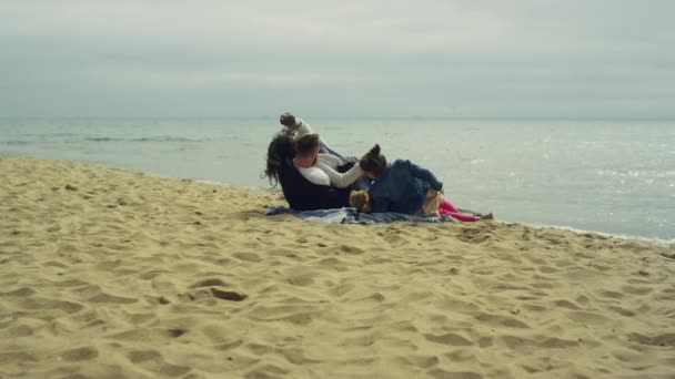 父母的孩子在平静的大海中享受海滨度假.一家人在野餐时玩耍. — 图库视频影像