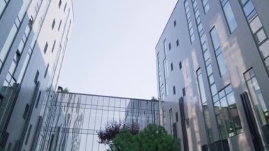 Gündoğumunda Avrupa İş Merkezi 'nin dış kısmı. Yeşil ağaçlarla döşenmiş bahçe.