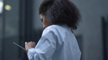 Modern ofis binasının dışında tablet bilgisayarda çalışan gülümseyen kadın..