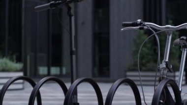 Yakın çekimde elektrikli scooter, siyah bisikletle ortak park yerinde duruyor..