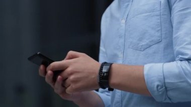 İş adamı dışarıda akıllı telefon mesajları kullanıyor. Erkek el tutma aygıtı yakın plan.