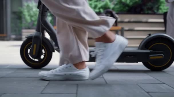 Primer plano piernas femeninas caminando con scooter eléctrico en el centro de la calle por la mañana. — Vídeos de Stock