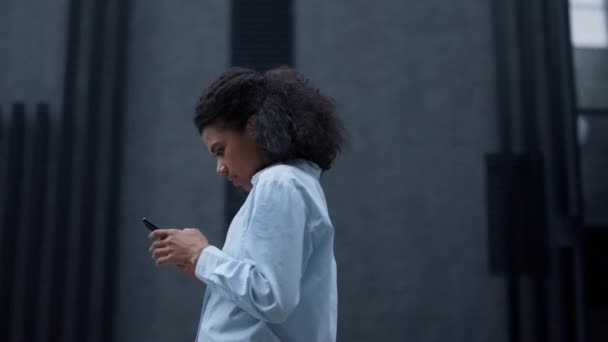 Vidám nő, aki üzenetet olvas, egyedül pózol a modern épületben. Sikeres menedzser — Stock videók