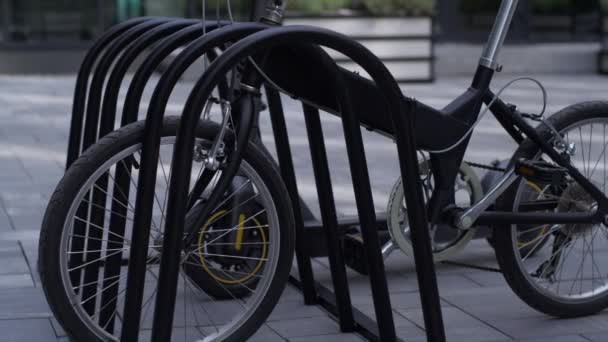 Scooter eléctrico de bicicleta negra de primer plano de pie en el estacionamiento compartido en la acera. — Vídeo de stock