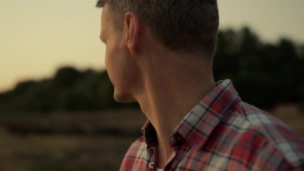 Αγρονόμος στέκεται χωράφι με σιτάρι στο ηλιοβασίλεμα αγροτικό τοπίο. Εκτροφέας οπίσθιας προβολής — Αρχείο Βίντεο