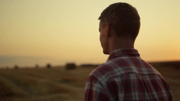 Landbouwers kijken machines op gouden zonsondergang landbouwgrond. Begrip landbouwbedrijf — Stockvideo