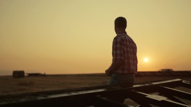 Rolnik badający zbiory na polu pszenicy o zachodzie słońca. Nowoczesna koncepcja agro. — Wideo stockowe
