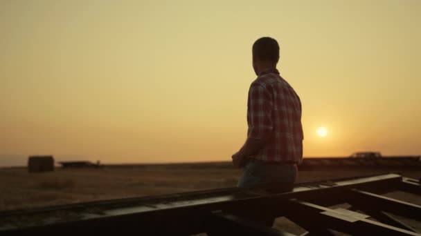 Contadino che esamina il raccolto sul campo di grano al tramonto dorato. Moderno concetto agro. — Video Stock