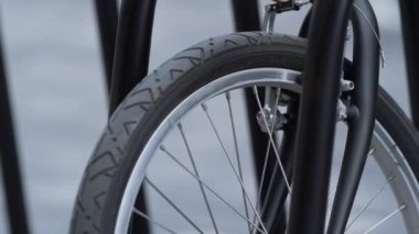 Yakın çekimde ön bisiklet tekeri ortak park yerinde duruyor. Alternatif taşıma.