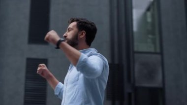 Şehir merkezinde zaferi kutlayan mutlu sakallı adam. Enerjik iş adamı