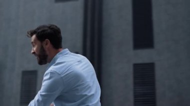 Ofis binasında poz veren gururlu iş adamı. Gülümseyen adam zafer anının tadını çıkarıyor.