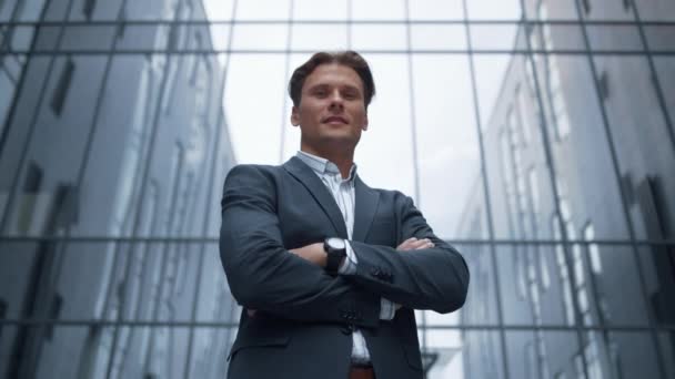 Portret uśmiechnięty biznesmen stojący samotnie przed szklanym budynkiem biurowym — Wideo stockowe