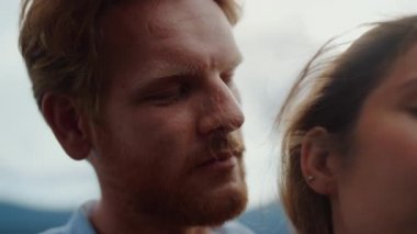 Tutkulu bir adam dışarıda bir kadının boynuna dokunuyor. Dağlarda buluşup eğlenen çift.