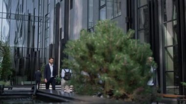 Kendine güvenen işadamı şehir merkezindeki ofis binasında yürüyor. Başarılı bir girişimci.