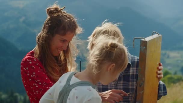 Mère peintre enseignant aux enfants dessiner en plein air. Famille heureuse créer image. — Video