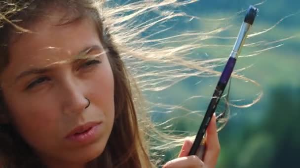 여름에 작업하는 클로즈업 화가입니다. 야외에서 눈을 찡그리는 생각깊은 소녀 — 비디오