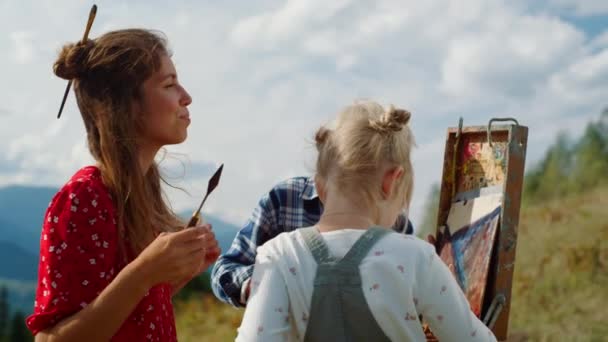 Famille heureuse créant image en plein air. Mère peinture enseigner les enfants en montagne — Video