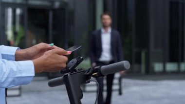 Kadın yakın planda elektrikli scooter kiralıyor. Şehir taşınabilirliği.