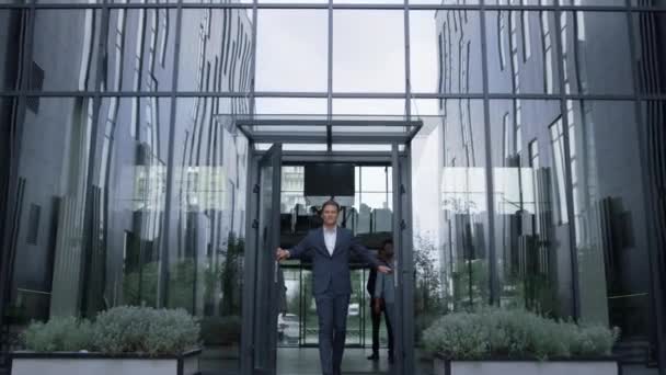Επιτυχημένος επιχειρηματίας στέκεται στην πόρτα του γραφείου κέντρο. Η ομάδα περιεχομένου φεύγει από το κτίριο — Αρχείο Βίντεο