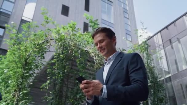 Attrayant message de type homme sur le téléphone marchant en costume gros plan. Style de vie du centre ville — Video