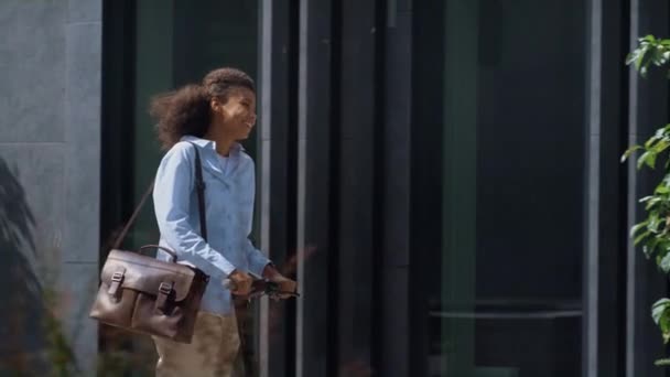 Cheerful manager riding electric scooter at office building. Urban traveler. — Stock Video