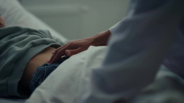 Een arts die de maag van een patiënt aanraakt. Ziek kind liggend in bed — Stockvideo