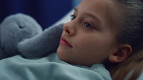 Porträtt flicka liggande i sängen med plysch leksak på sjukhus kontroll i pediatriska enheten. — Stockvideo