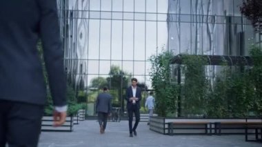 Kendine güvenen yöneticiler iş merkezinin yeşil bahçesinde yürüyor. İş insanları kavramı