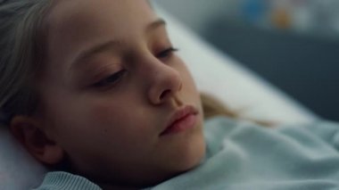 Hasta kız hastane yatağında tek başına yatıyor. Sıkılmış çocuk acil serviste dinleniyor..