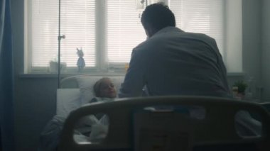 Çocuk doktoru hastane koğuşundaki küçük hastayı muayene ediyor. Klinikte yatan kız.