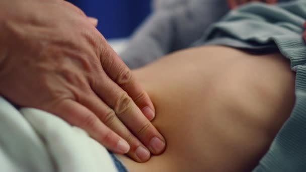 Las manos del doctor tocando el primer plano del estómago. Niña enferma acostada en la cama del hospital. — Vídeo de stock