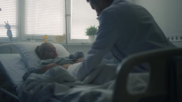 Kranke Ärztin sitzt in der Nähe des Bettes Rückansicht. Ärztliche Untersuchung im Krankenhaus. — Stockvideo