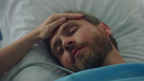 Zieke patiënt liggen in bed na chirurgische behandeling. Vrouwelijke hand aanraking gezicht close-up — Stockvideo