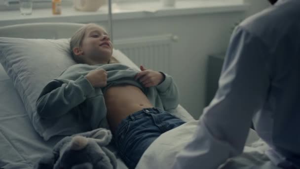 Lekarz odwiedza oddział pacjenta po zakończeniu terapii. Cute girl leżące w łóżku szpitalnym. — Wideo stockowe