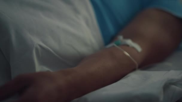 Patient liegt nach chirurgischer Behandlung in Nahaufnahme im Bett. Besorgter Besucher sitzt am Mann — Stockvideo