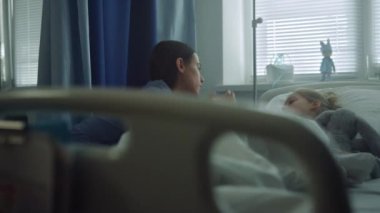 Anne kız koğuşunu el ele tutuşarak ziyaret ediyor. Destekleyici ebeveyn, hasta çocuğu rahatlatıyor