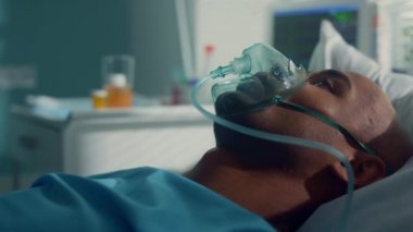 Doktor, kovid19 tüplerini klinik testi için al. Hasta oksijen maskesi takmış yatıyor.