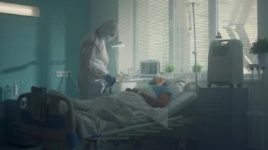 Enfeksiyon ünitesi koğuşunda kan basıncını sphygmomanometre ile ölçen bir doktor.