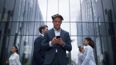 Düşünceli iş adamı şehir merkezinde akıllı telefon kullanarak dışarıda mesaj atıyor..