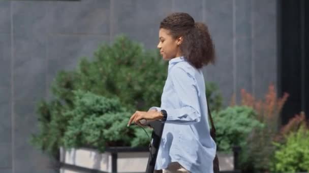 Mujer sonriente caminando con scooter en manos de la calle de la ciudad. Concepto de viajero urbano. — Vídeos de Stock