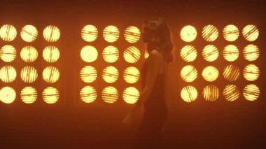 Kulüp lambalarının yanında el ele dans edin. Kadın avucuna dokunan adam uzaklaşıyor.