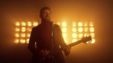 Müzisyen adam sahne gece kulübünde solo performans sergiliyor. Gitar çalan vokalist.