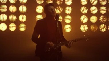 Sahnede gitar çalan bir adam. Adam kulüpte şarkı söylüyor..