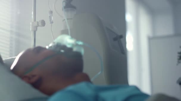 Recuperando paciente com máscara de oxigênio deitado no leito unidade de emergência perto da enfermaria. — Vídeo de Stock