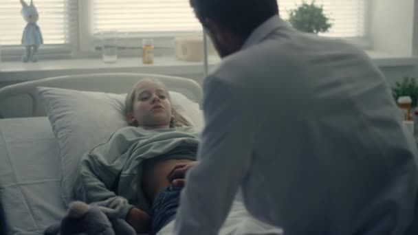 Doctora palpitante dolor de estómago en la sala. Niño enfermo acostado en la cama del hospital. — Vídeos de Stock