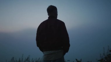 Rahat adam sahada güneşin doğuşunu seyrediyor. Sakin adam dağ manzarası arıyor.