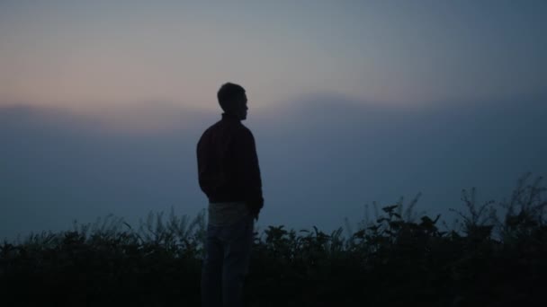 Uomo pacifico godendo paesaggio nebbioso al mattino. Ragazzo in piedi sulla montagna — Video Stock